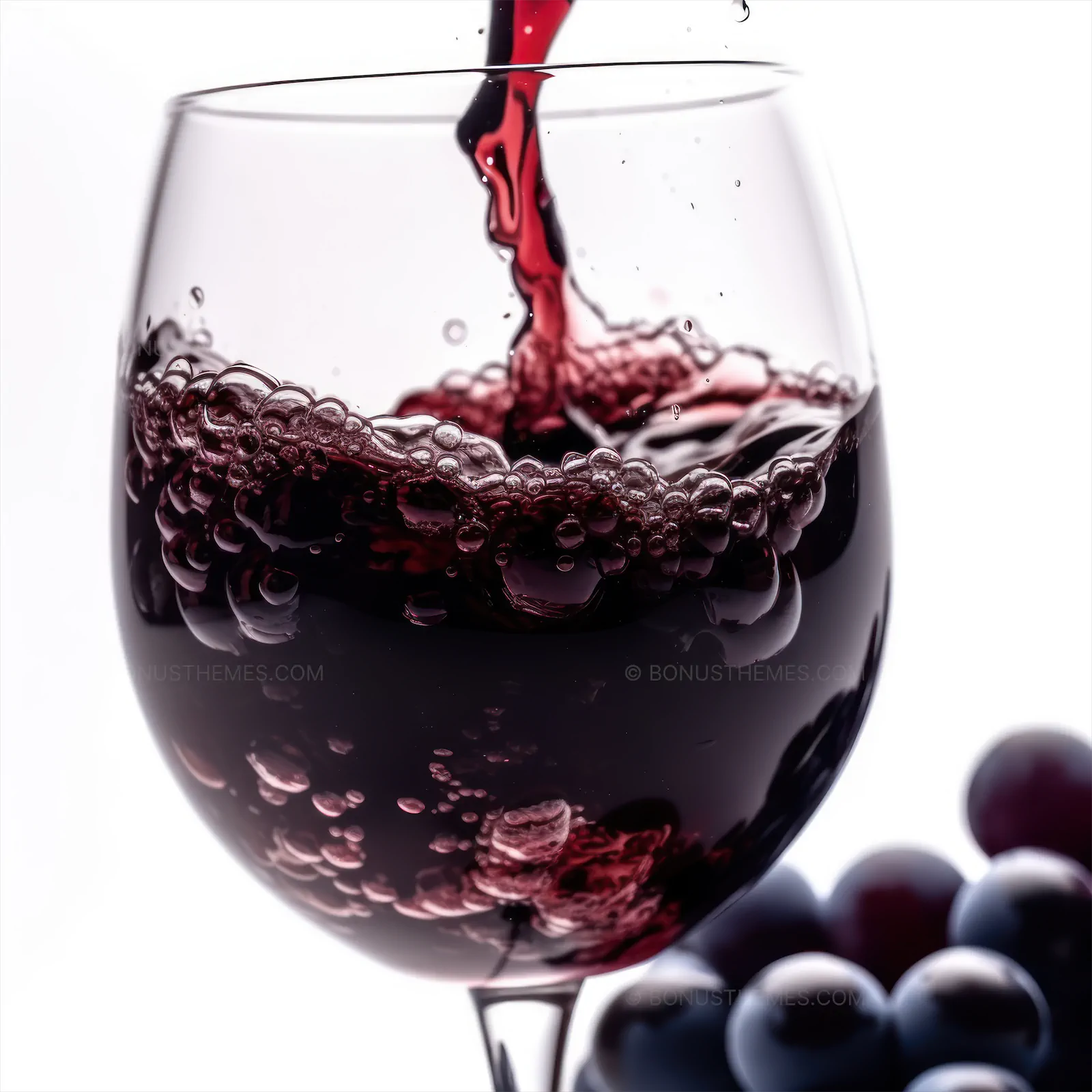 A red wine being poured into a glass with grapes,